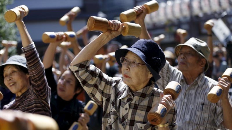 Personas de edad avanzada edad hacen ejercicio con pesas de madera durante un evento de promocion de la salud en Tokio